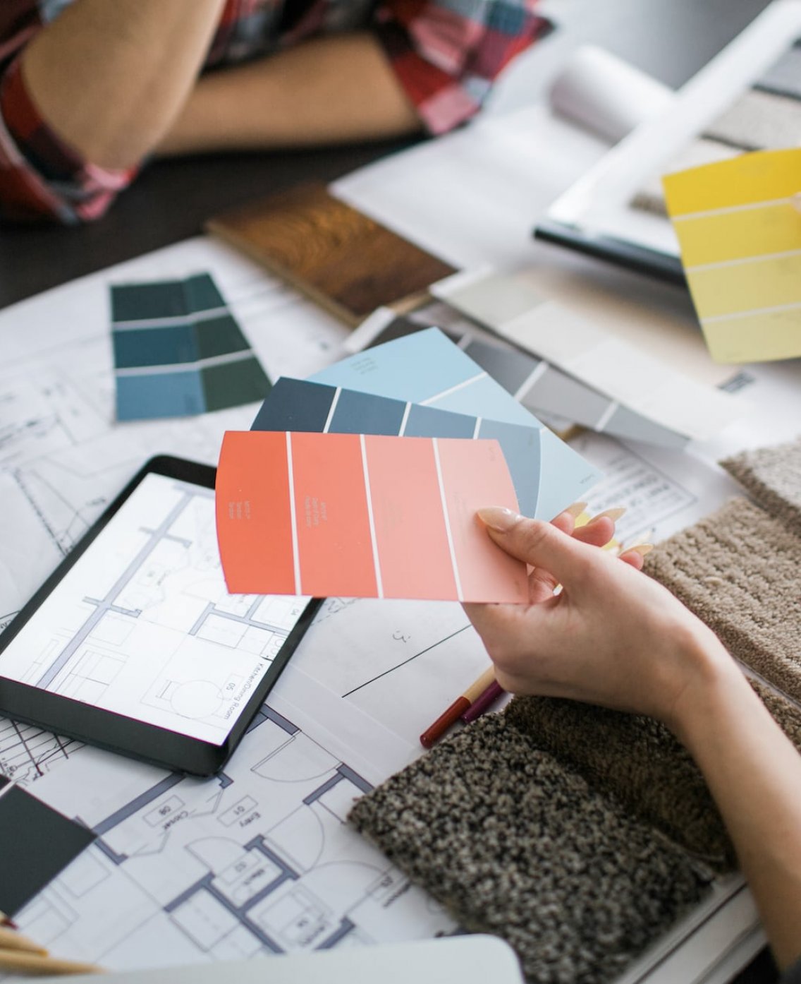 Raumaussttater berät Kunden mit Farbmustern und Teppichmustern