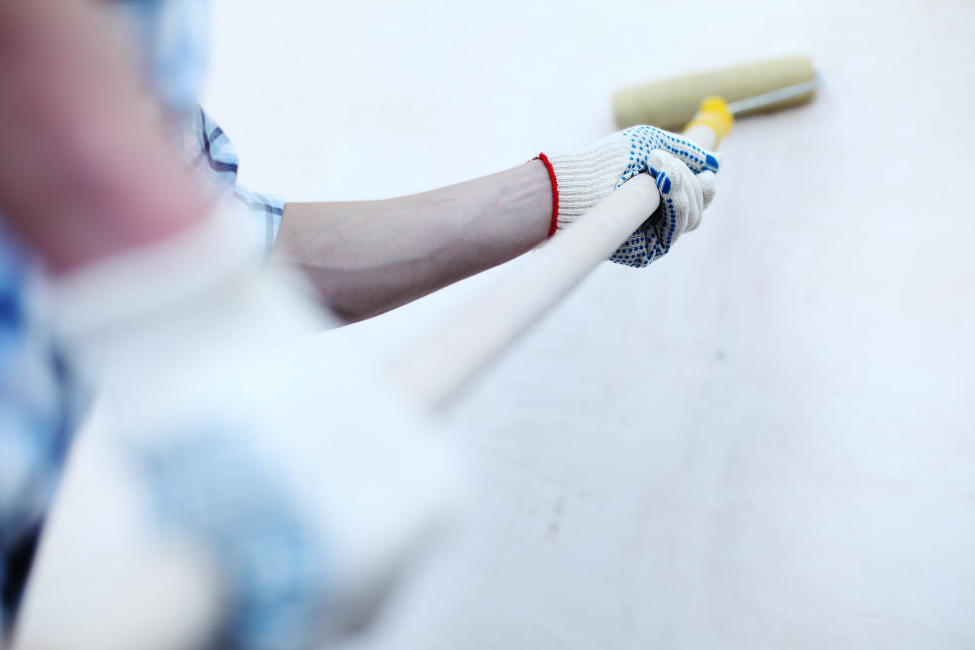 Maler streicht Fassade mit weißer Farbe